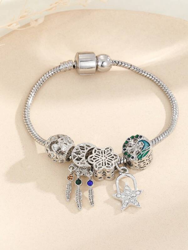 Silver-toned star and moon charm bracelet with sparkling accents and secure clasp on a beige background.